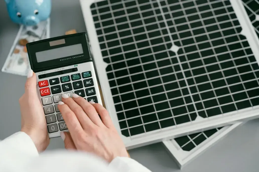 A person is using a calculator in front of a solar panel.
